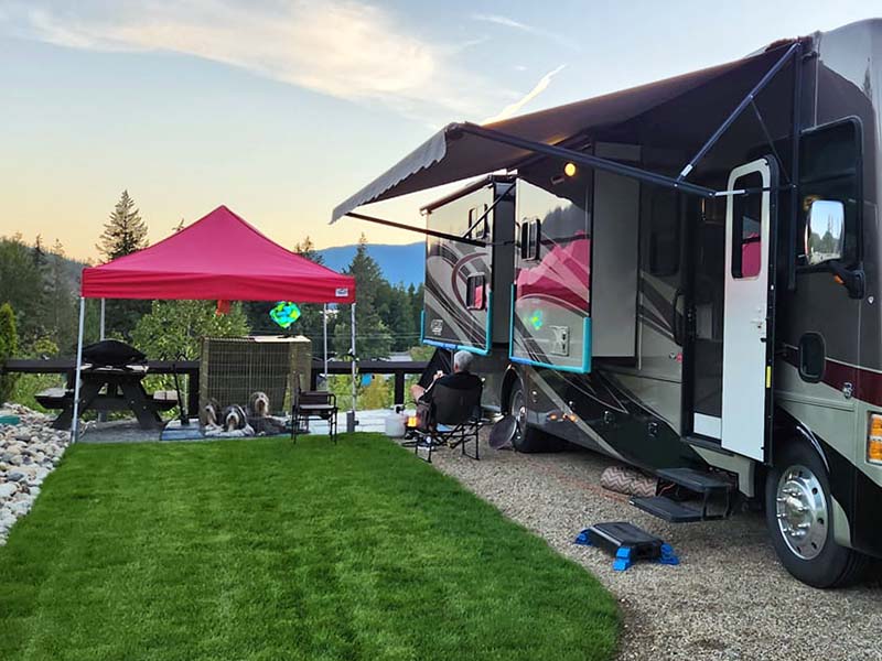 A man and his dogs sitting outside their Motorhome enjoying a warm evening at Mara Lake RV Park and Campground.